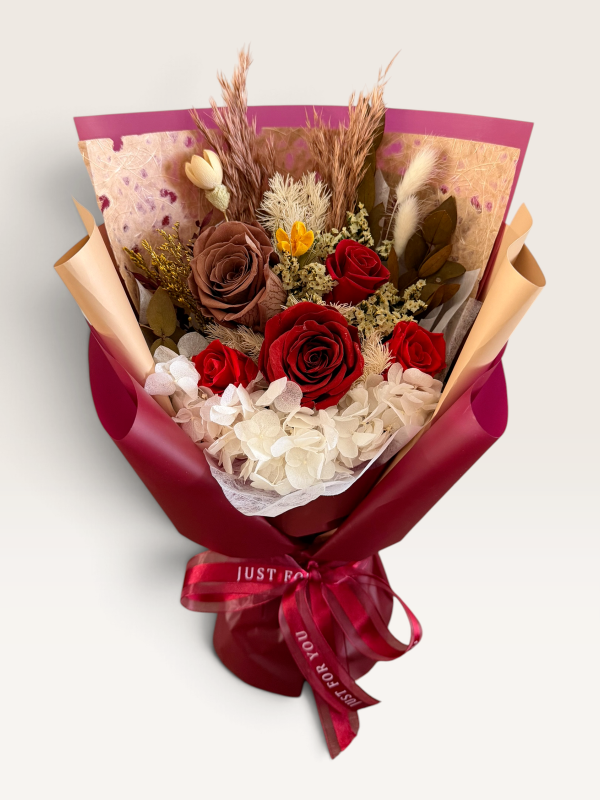 Autumn Embrace bouquet with red and brown preserved roses, ivory hydrangea and burgundy wrapping