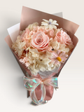Blush Whisper preserved flower bouquet with pink roses, cream and blush hydrangeas, pink wrapping and an iridescent bow
