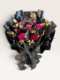 Fuchsia Majesty preserved rose bouquet in black wrapping with gold foliage and pearl accents
